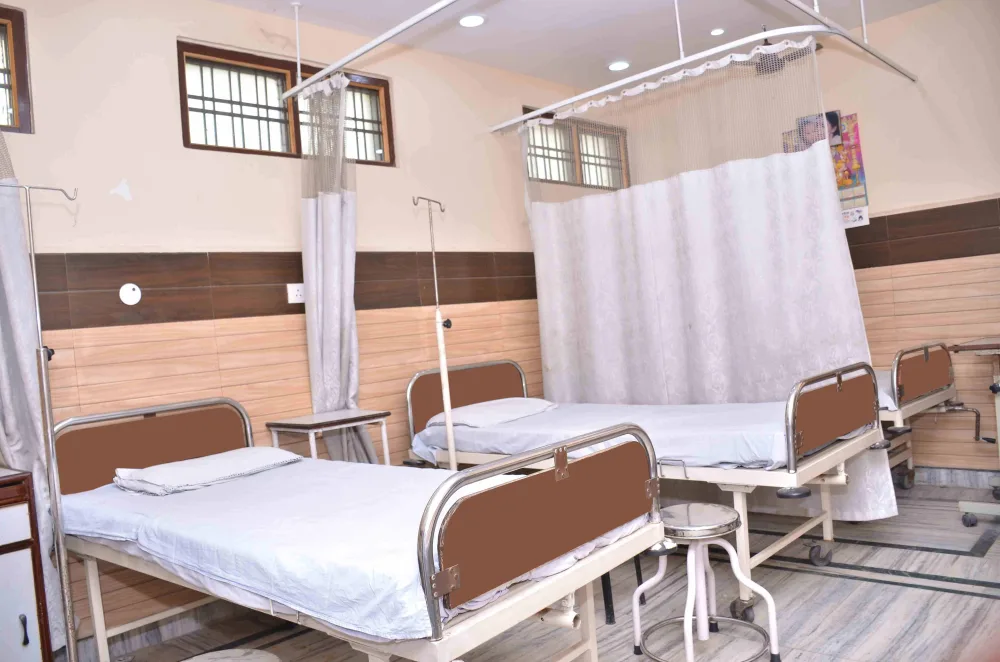 Hospital beds with bedside stools in a ward with privacy curtains