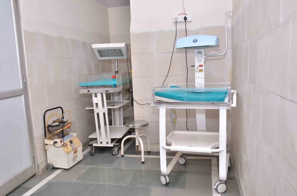 Infant care cot beneath an overhead warmer beside a monitor